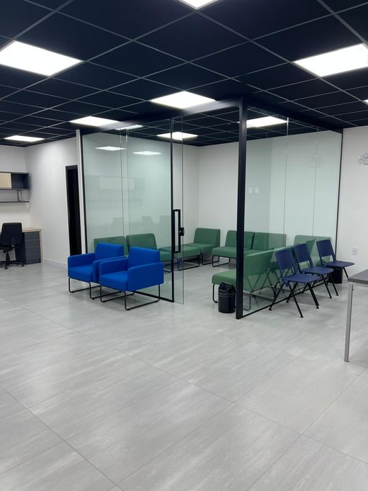 Área de espera com poltronas azuis e salas com divisórias de vidro